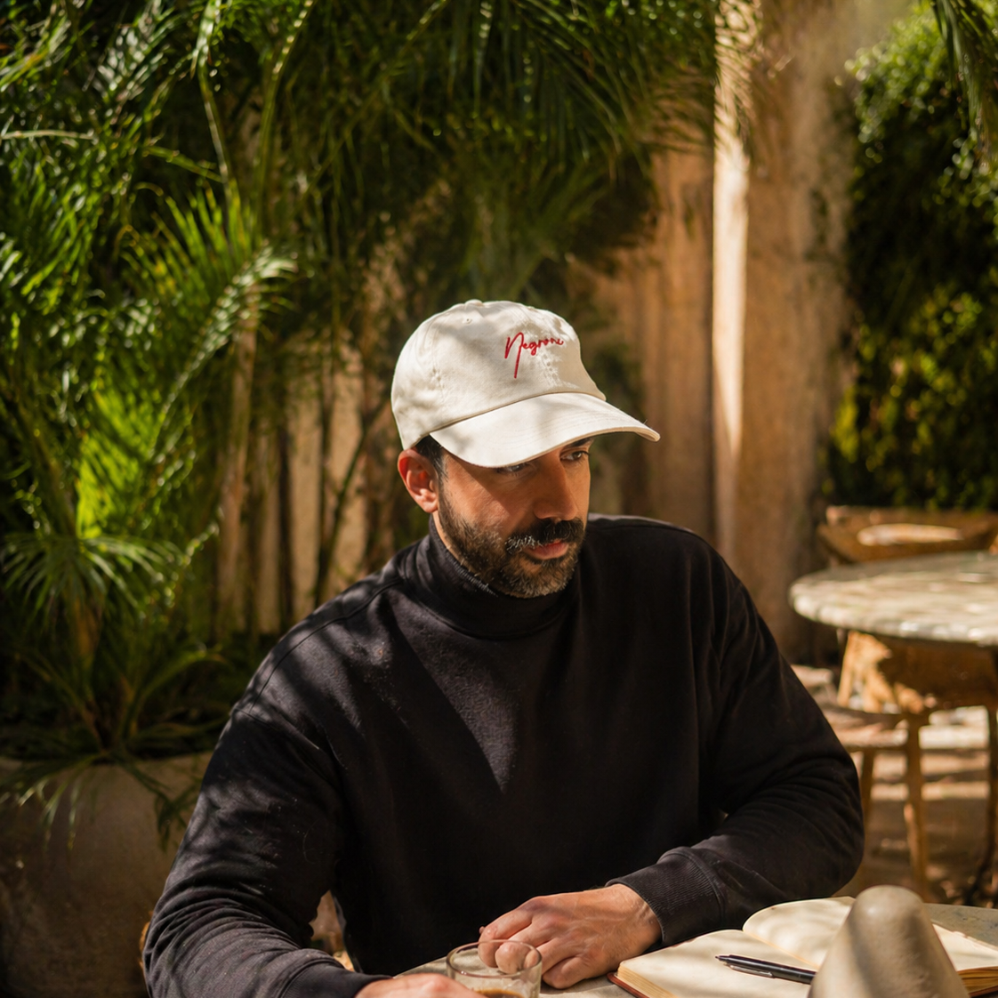 Man sitting at a table outdoors with plants in the background